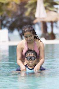 Mother and sons enjoying in swimming-pool on summer season.