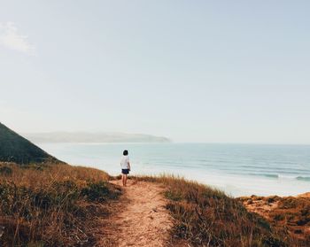 Rear view of man looking at sea against sky