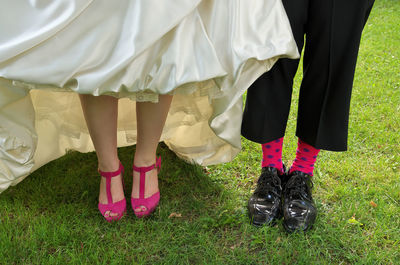A whimsical close up of a bride with pink high heels and groom with funky socks