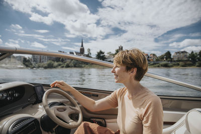 Man sitting on boat in river against sky