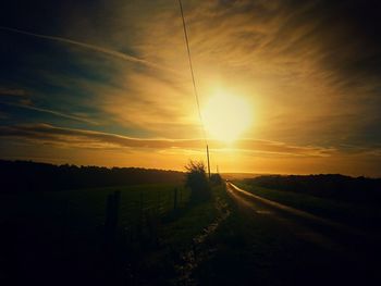 Scenic view of silhouette field against cloudy sky during sunset