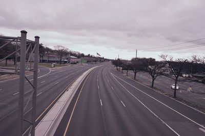 Road passing through city against sky