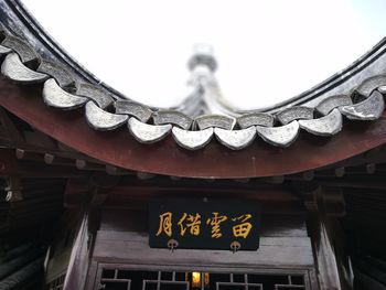 Low angle view of text on building roof against sky