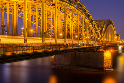 Illuminated bridge over river at night