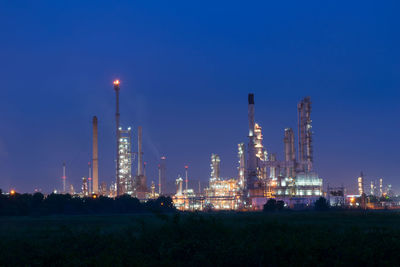 Illuminated factory against sky at night