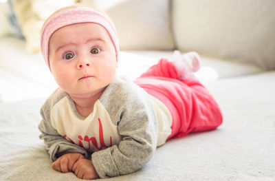 Portrait of cute baby girl lying on bed at home