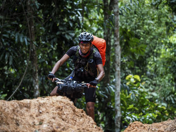 Portrait of man cycling against trees