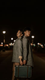 Young couple standing in illuminated city at night