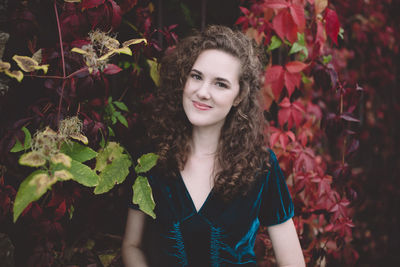 Beautiful curly hair young woman in dark blue velvet dress in an autumn park