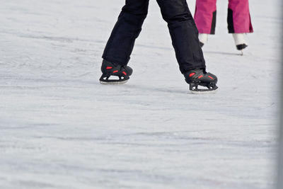 Low section of people ice-skating on ice rink during winter