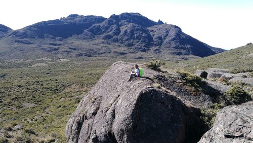 Rear view of man sitting on cliff