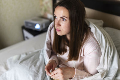 Portrait of young woman sitting on bed at home