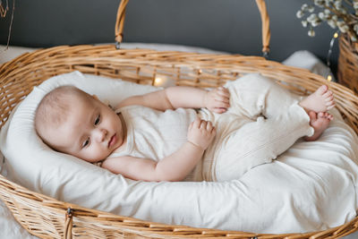 Baby lies in a wicker basket gray background willow eco style