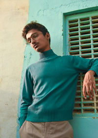 Portrait of young man standing by window