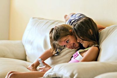 Father and daughter while sitting on sofa at home