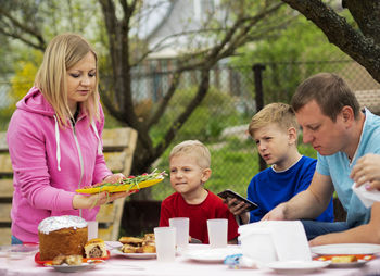 Woman serving food to sons and man outdoors