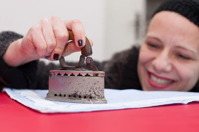 Close-up of smiling woman ironing fabric on table