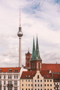 Fernsehturm and buildings against cloudy sky