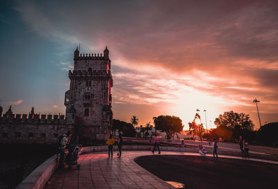 People in city against sky during sunset