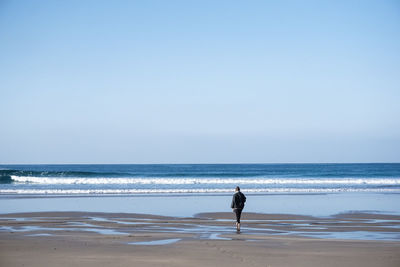 Woman on beach against clear sky