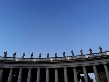 Low angle view of people against clear blue sky