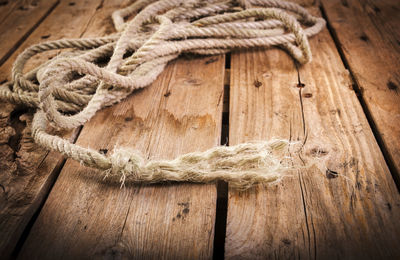 Close-up of rope tied on wooden plank