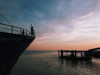 Silhouette people standing on pier by sea against sky during sunset