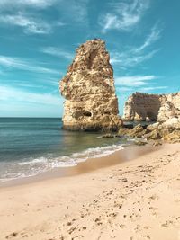 Rock formation on beach against sky