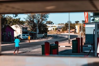 Rear view of man walking on street against buildings