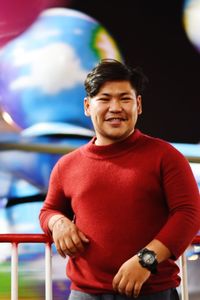 Young man smiling while standing against railing