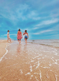 Women on beach against sky