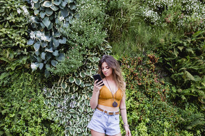 Young woman standing against plants