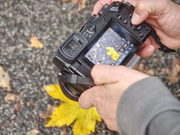Woman taking pictures with a mirrorless camera in forest in the fall season. leaves fallen on ground