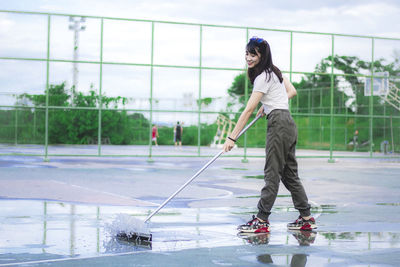 Young woman cleaning water from basketball court
