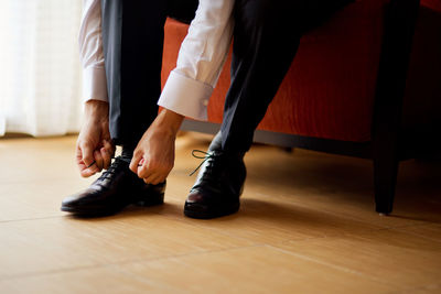 Low section of man tying shoelace at home