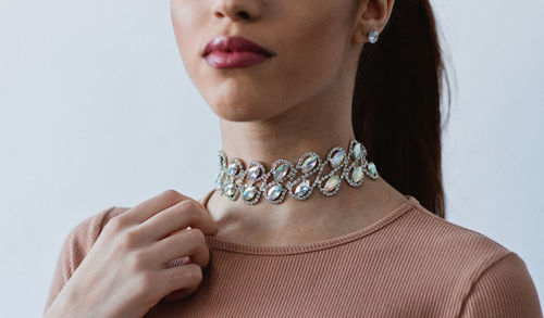 Midsection of woman wearing necklace against white background