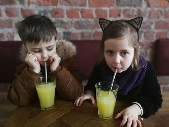 Siblings drinking juice in restaurant