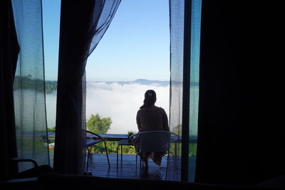 Rear view of man sitting on glass window