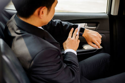 Businessman looking at smartwatch while sitting in car