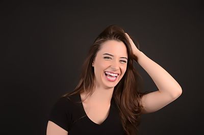 Young woman smiling against black background