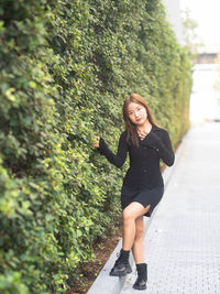 Portrait of young woman standing against trees