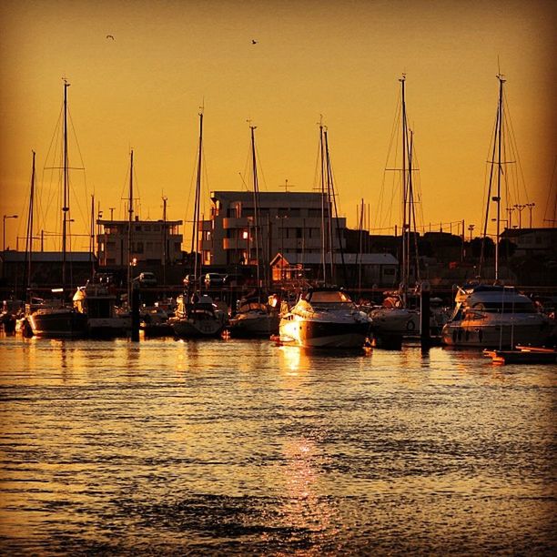 transportation, nautical vessel, mode of transport, sunset, moored, boat, water, orange color, mast, harbor, waterfront, sailboat, sea, sky, travel, reflection, building exterior, outdoors, marina, river