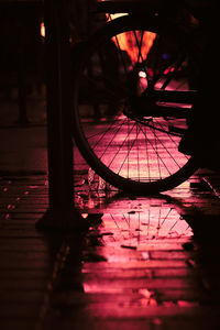Reflection of illuminated bicycle in puddle
