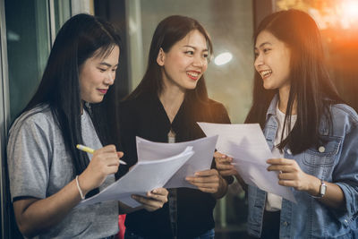 Cheerful colleagues holding papers while standing at office