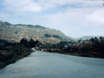 Road by mountains against sky during winter