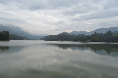 Scenic view of lake and mountains against cloudy sky