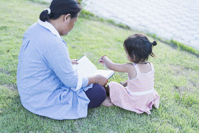 Rear view of woman sitting on grassy field