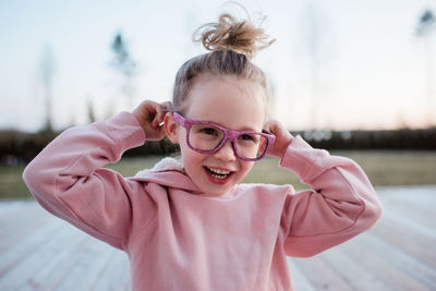 Portrait of a young girl pulling silly faces with pink sparkly glasses