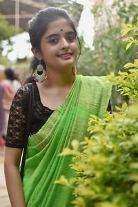 Portrait of young woman standing against plants