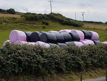 Stack of hay bales in farm against sky